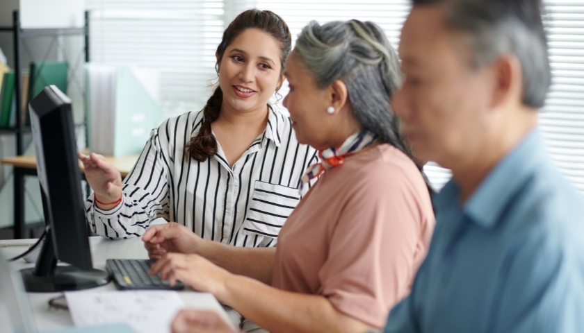 Three people talking and looking at desktop computer