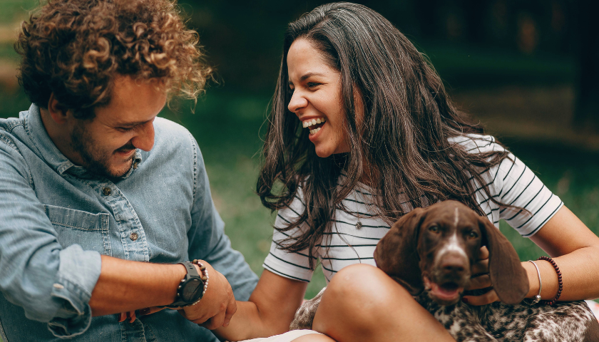 couple laughing outside with their dog