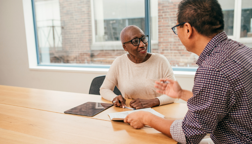 Woman and man talking while sitting at table.