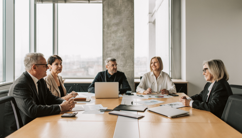 group of men and women business people sitting around table