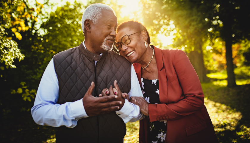 Older couple walking outside smiling and leaning into each other