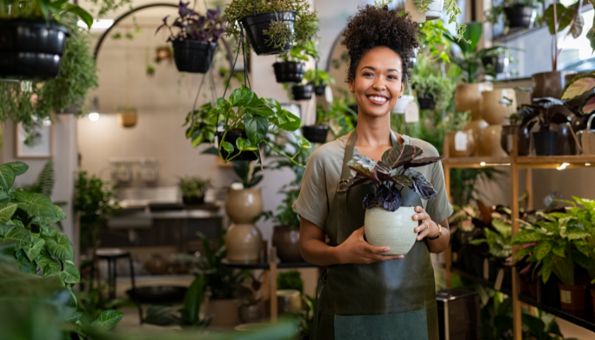 Young business owner in plant store smiling at camera
