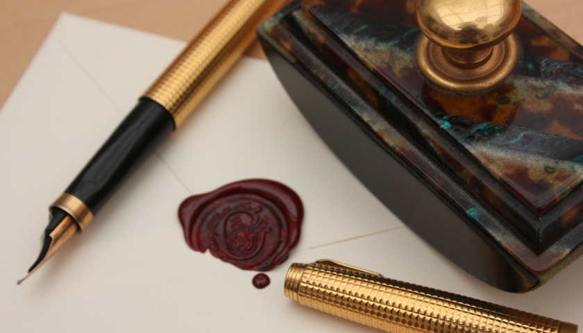 Gold pen on piece of paper with wax seal.